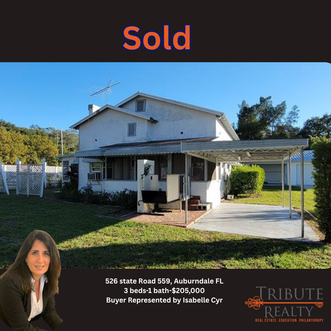 A white house with a carport and a lawn, sold for $265,000 in Auburndale, FL, presented by Tribute Realty.