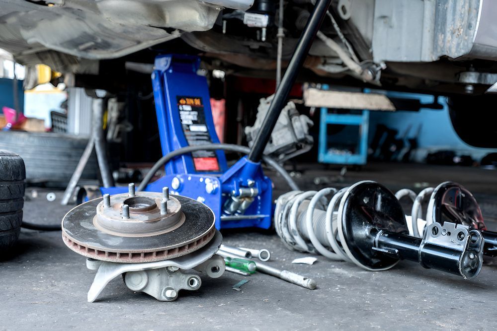A Car Break Is Being Repaired In A Garage With A Blue Jack — Border Bandag Tyre Service In South Albury, NSW