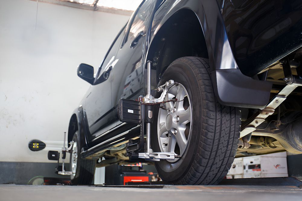 A Wheel Is Being Adjusted On A Lift In A Garage — Border Bandag Tyre Service In South Albury, NSW