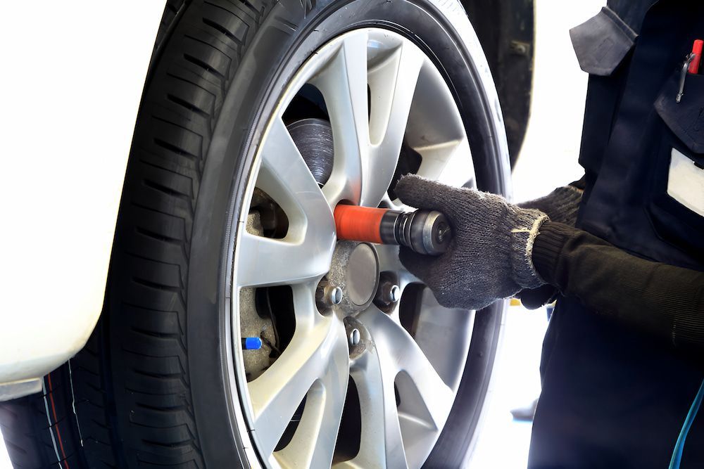 A Person Is Working On A Car Wheel With A Wrench — Border Bandag Tyre Service In South Albury, NSW