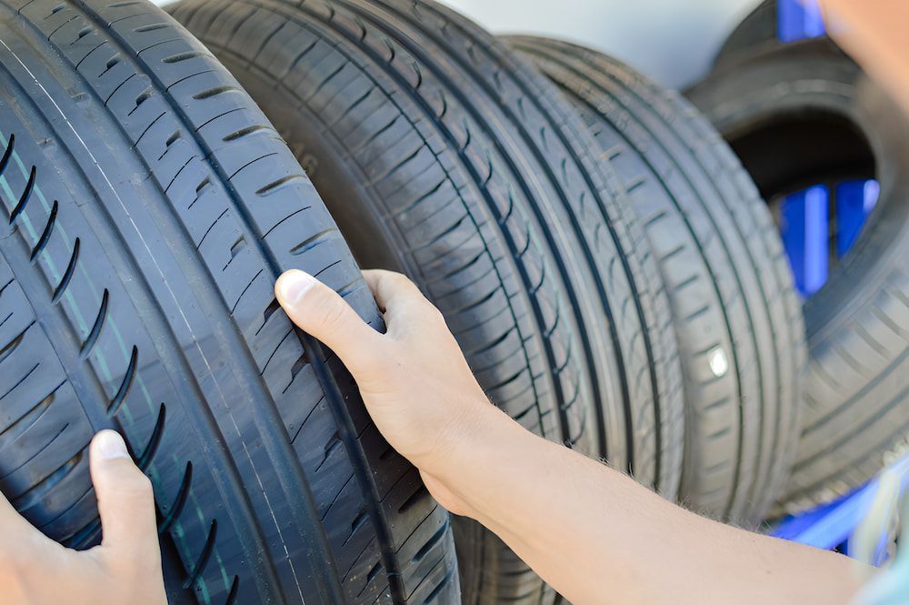 A Person Is Holding A Tire In Front Of A Pile Of Tires — Border Bandag Tyre Service In South Albury, NSW