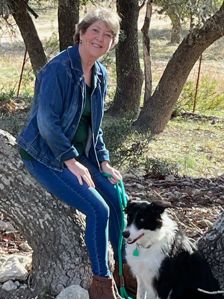 A woman is sitting on a tree branch next to a dog.