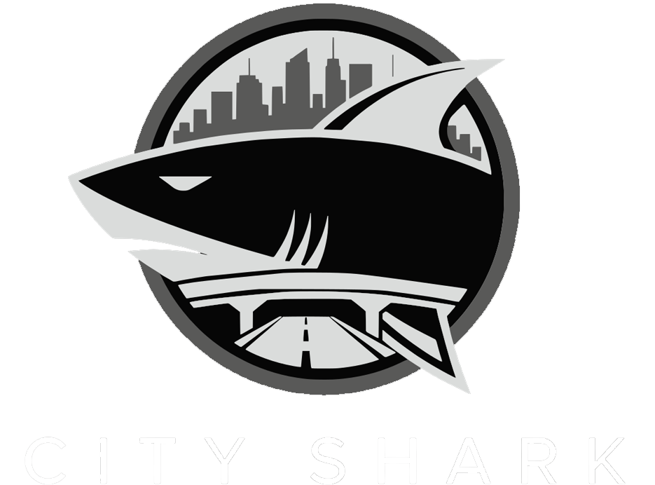 Black-and-silver shark logo in a circular emblem with a city skyline in the background