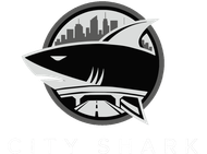 Black-and-silver shark logo in a circular emblem with a city skyline in the background