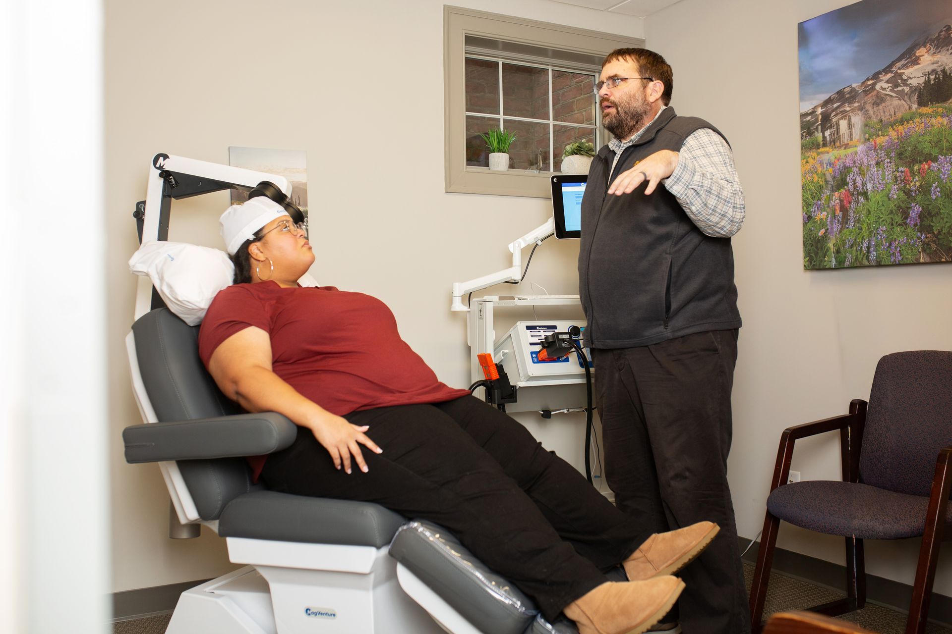 A person reclined in a medical chair listens to a doctor who gestures, in a doctor's office.