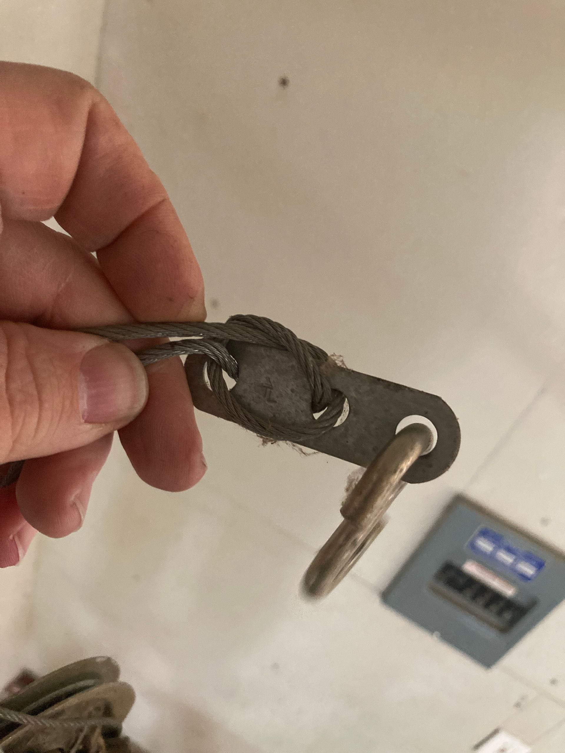Hand holding a frayed keychain with a metal key in front of a wall-mounted device.