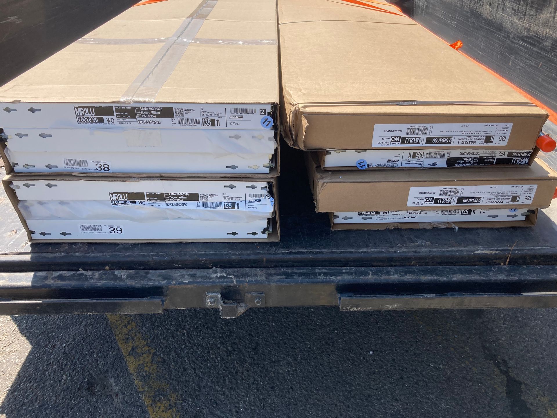Stacked cardboard boxes in the back of a truck on a sunny street.