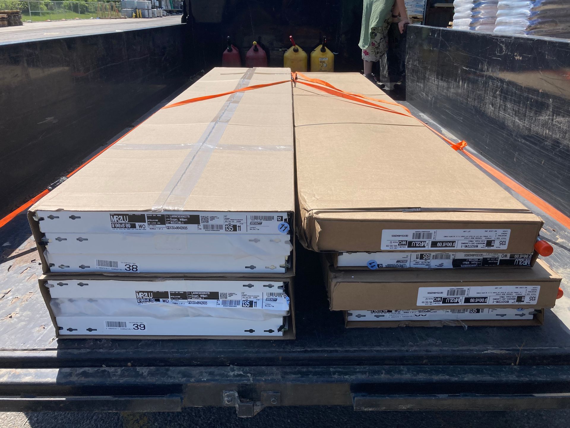 Two large strapped cardboard boxes loaded on a flatbed truck, seen from the rear.