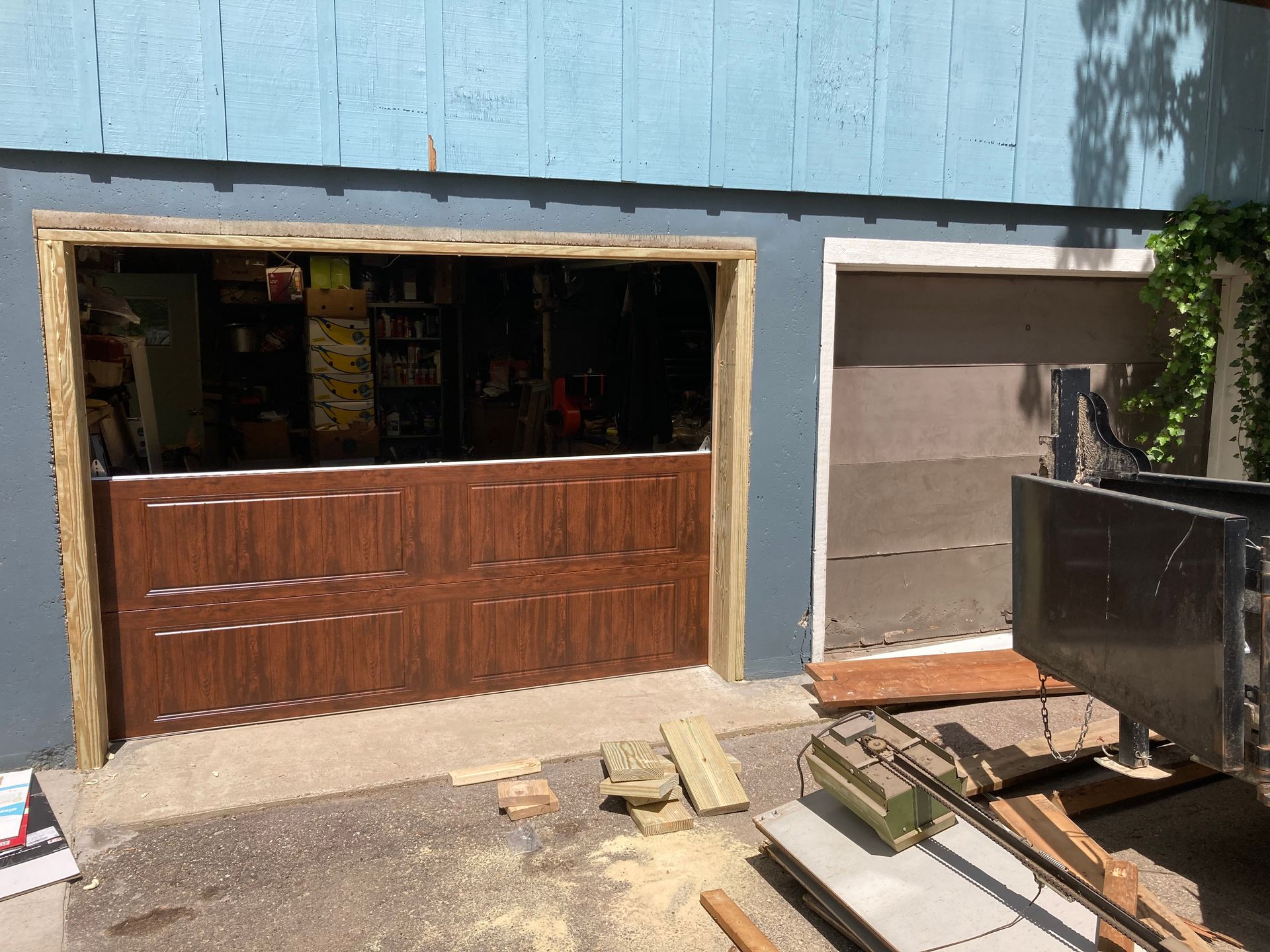 Open storefront with wooden counter and a closed garage door beside a parked trailer.