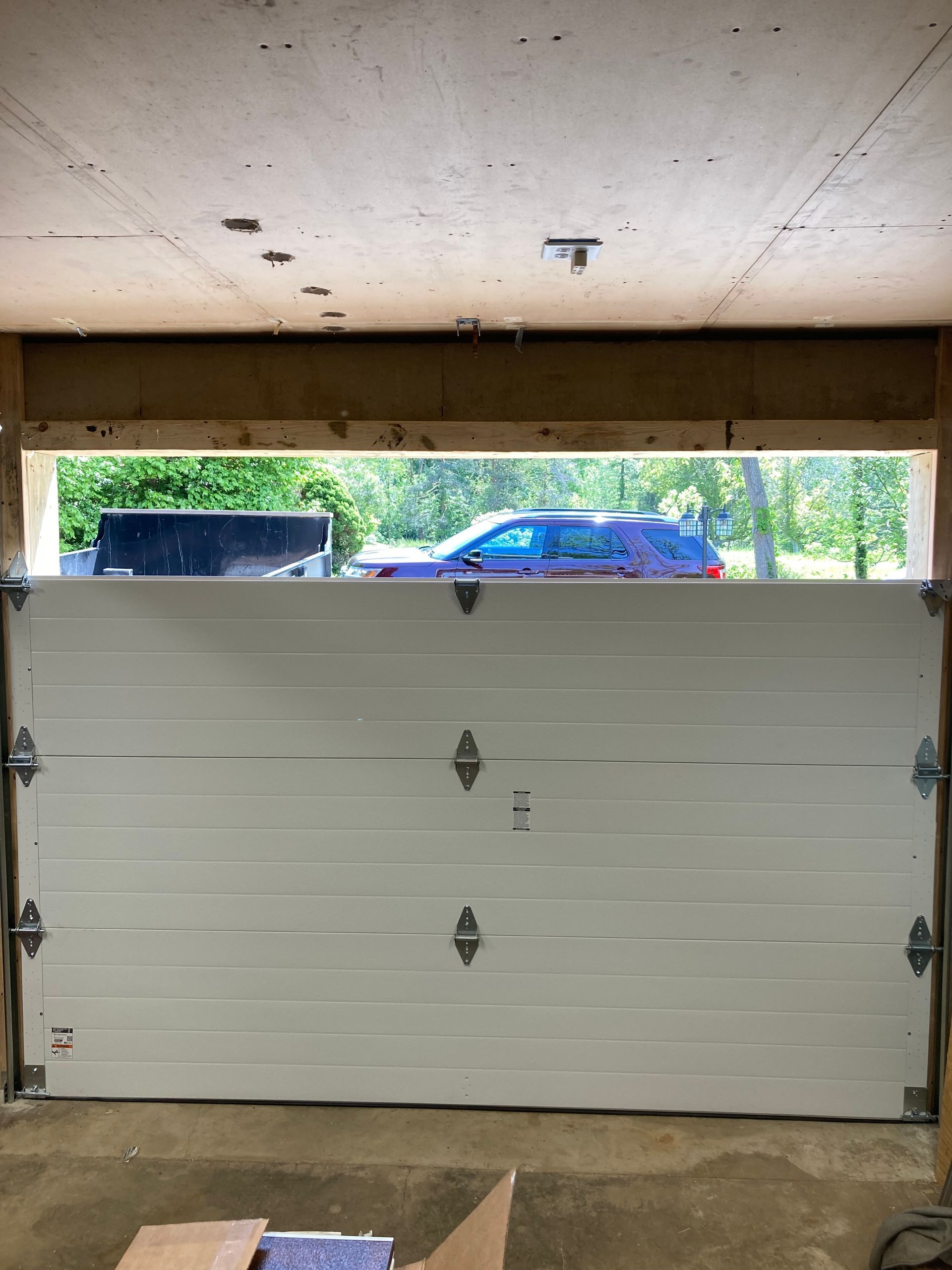 Partially open garage with a white sectional door and parked cars visible outside