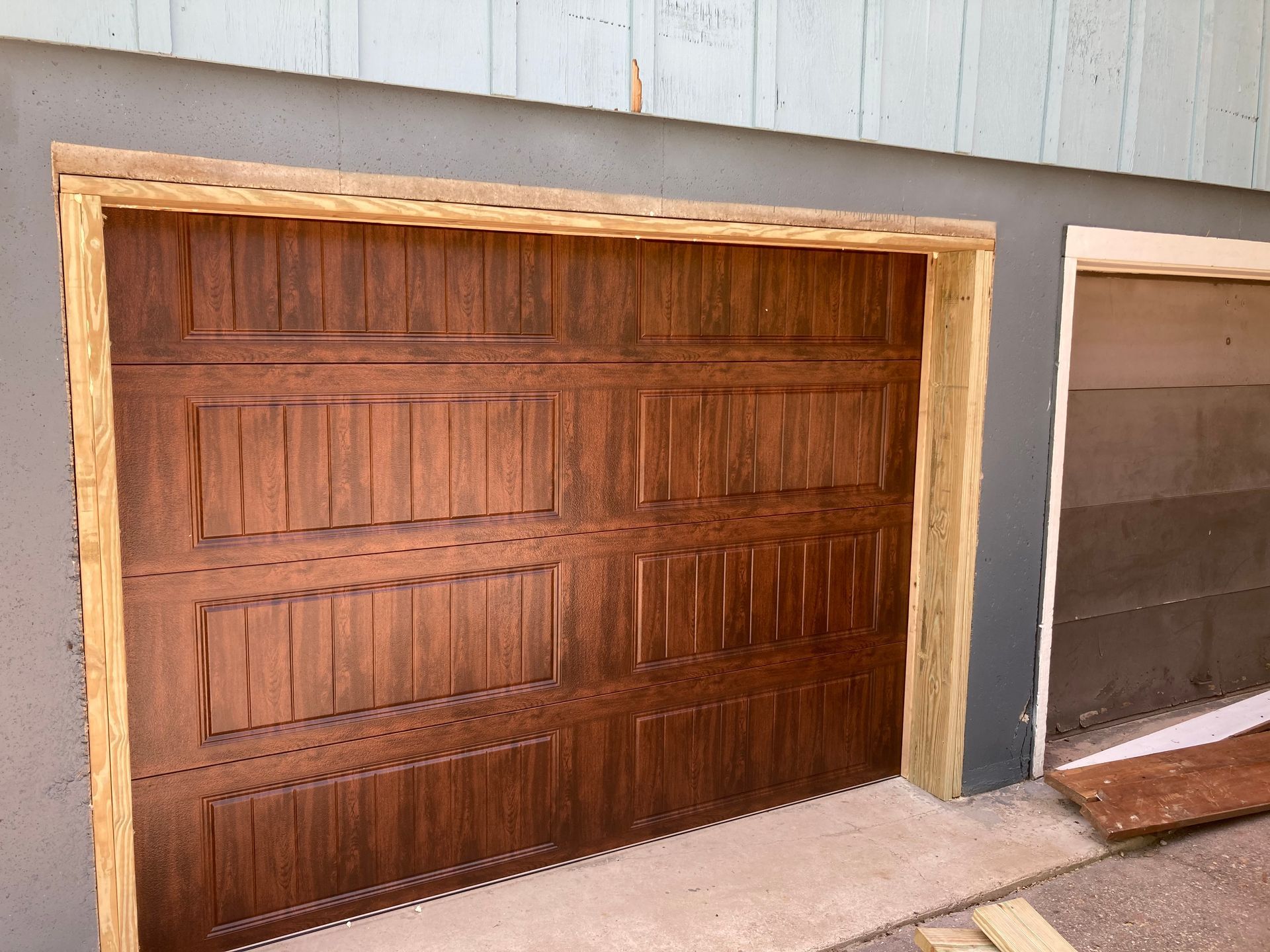 Wooden garage door with vertical panels set in a light gray exterior wall