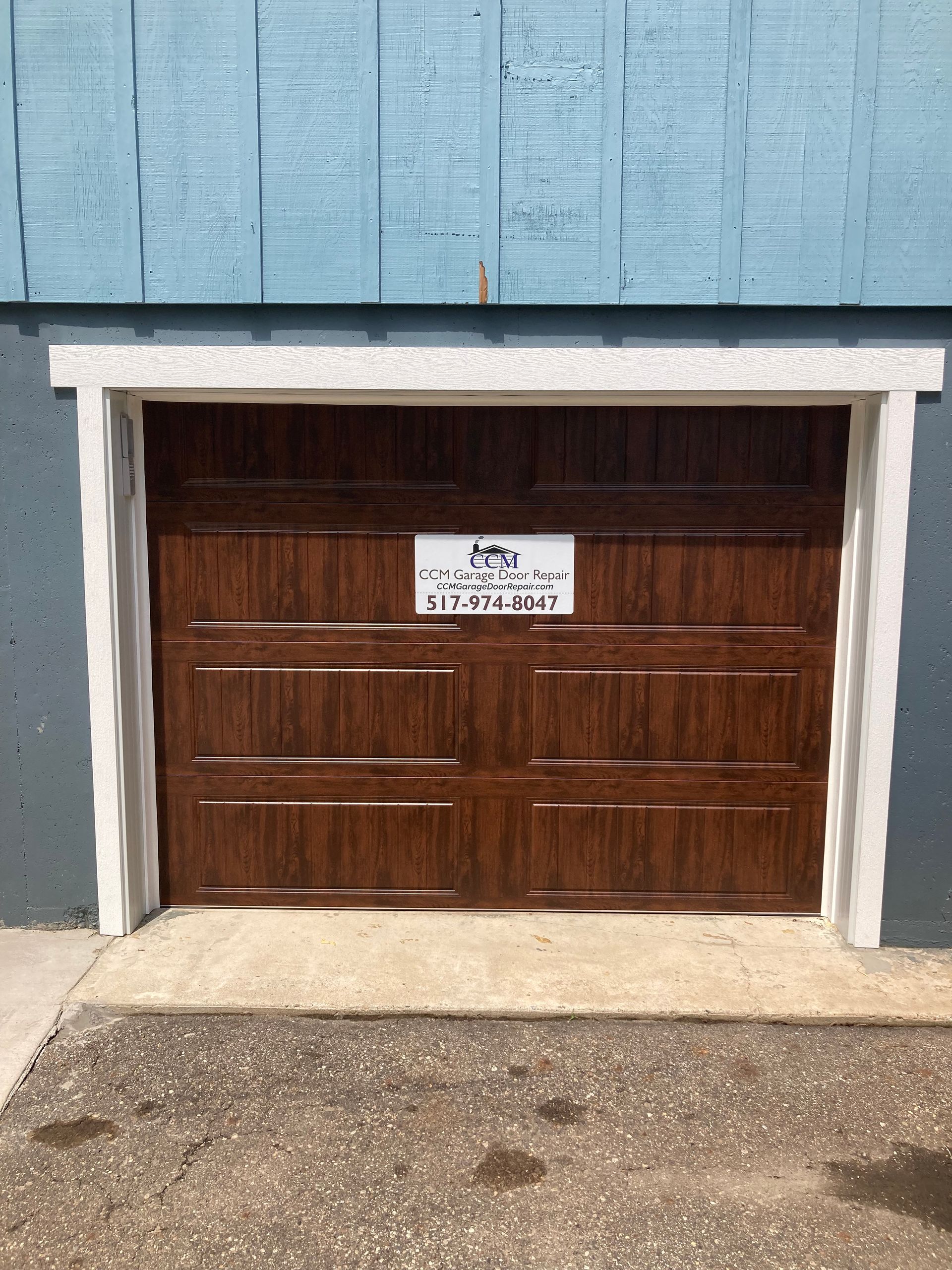 Wooden garage door in a blue building with a small sign above it.