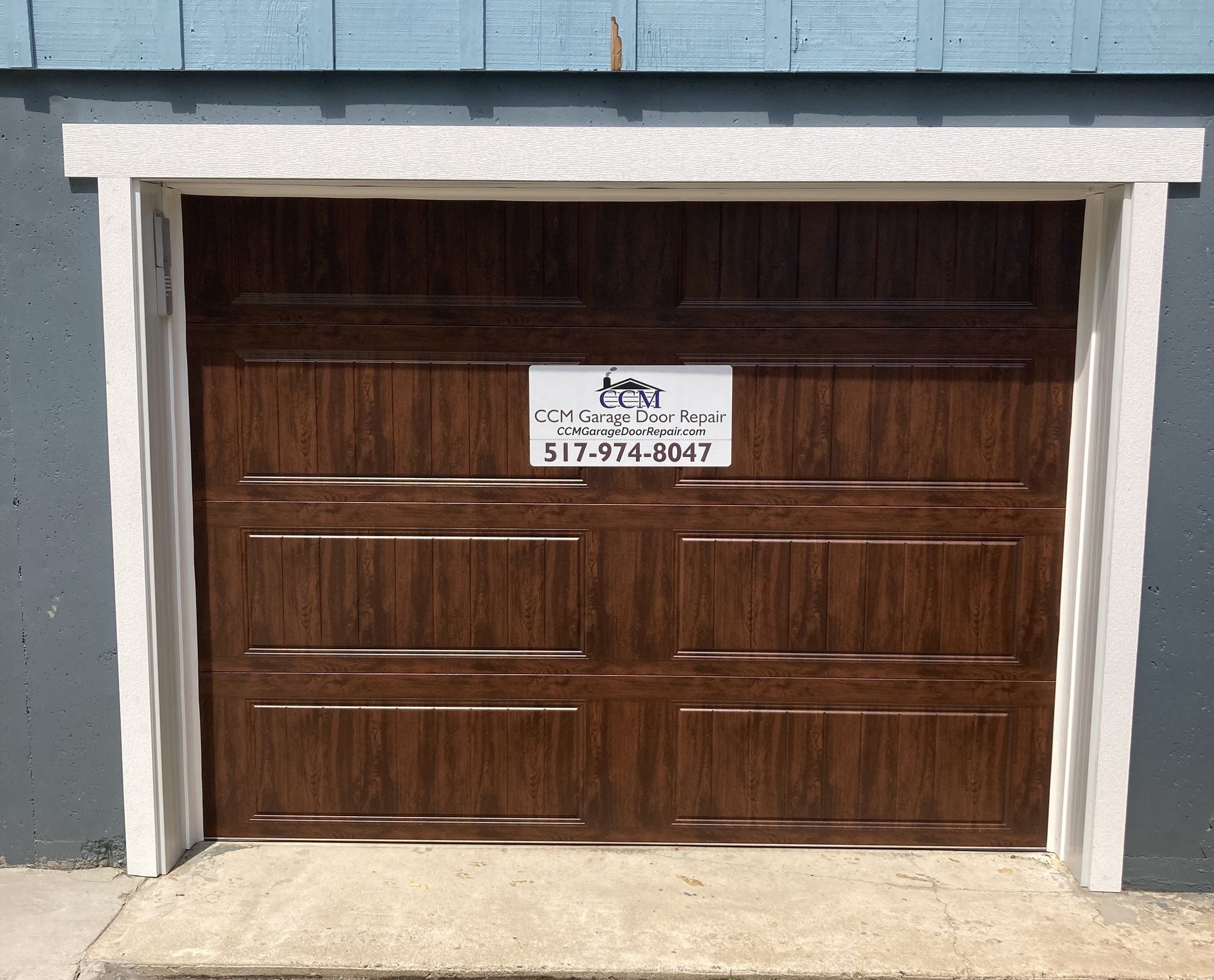 Wooden garage door with a small sign, set in a blue-gray building facade