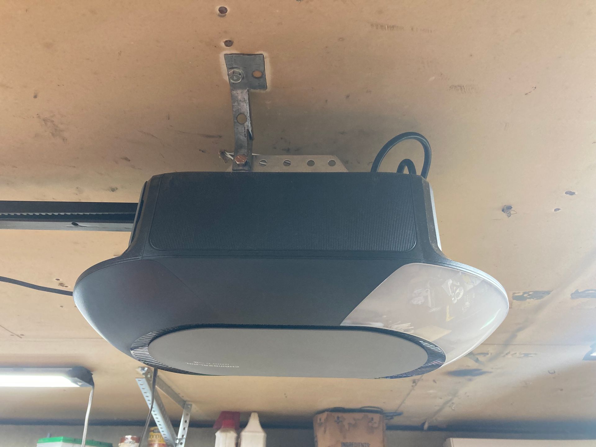 Ceiling-mounted garage door opener with black and white housing on a beige ceiling