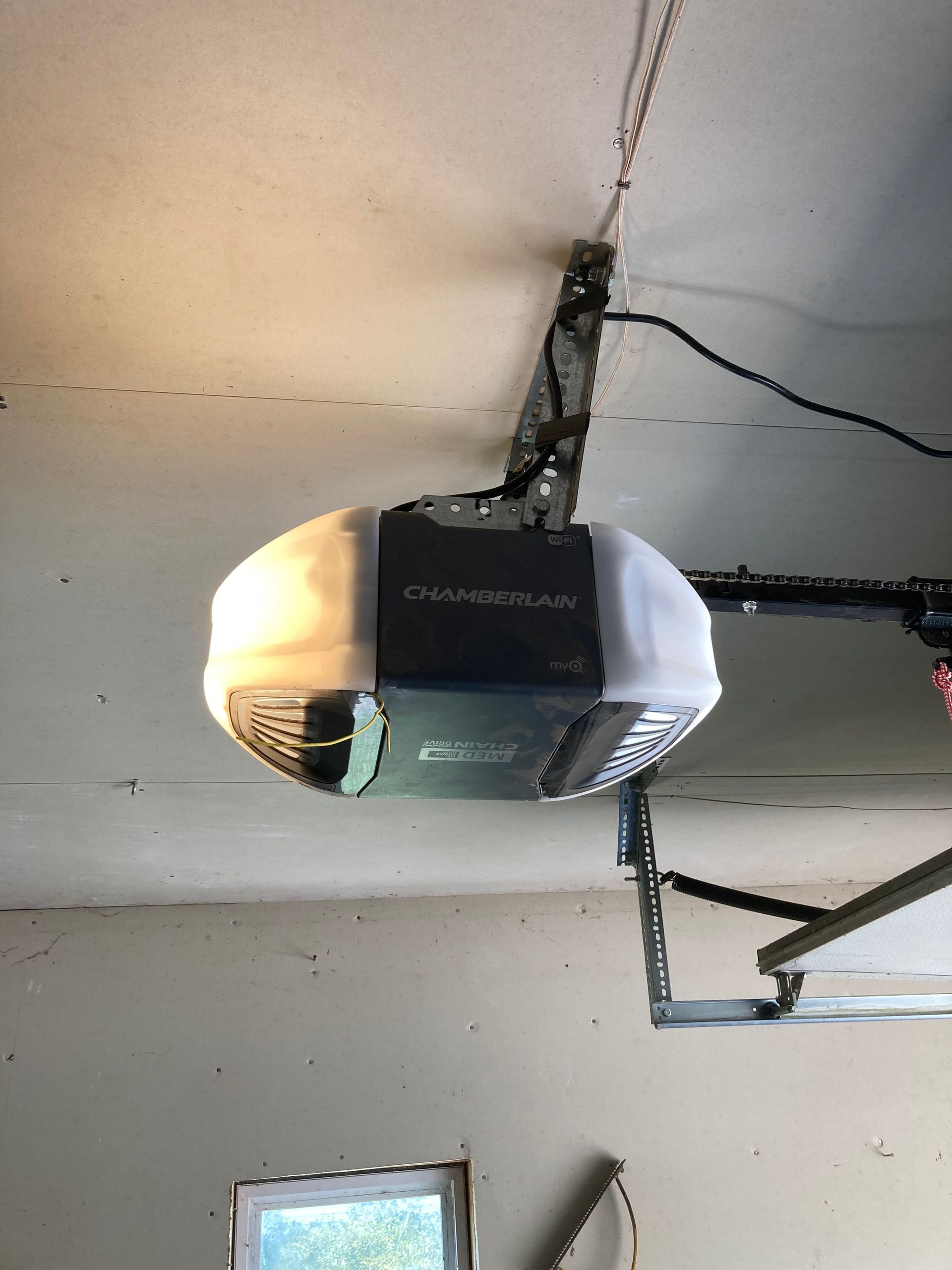 Damaged garage door opener hanging from ceiling with a cracked mounting point and exposed wiring