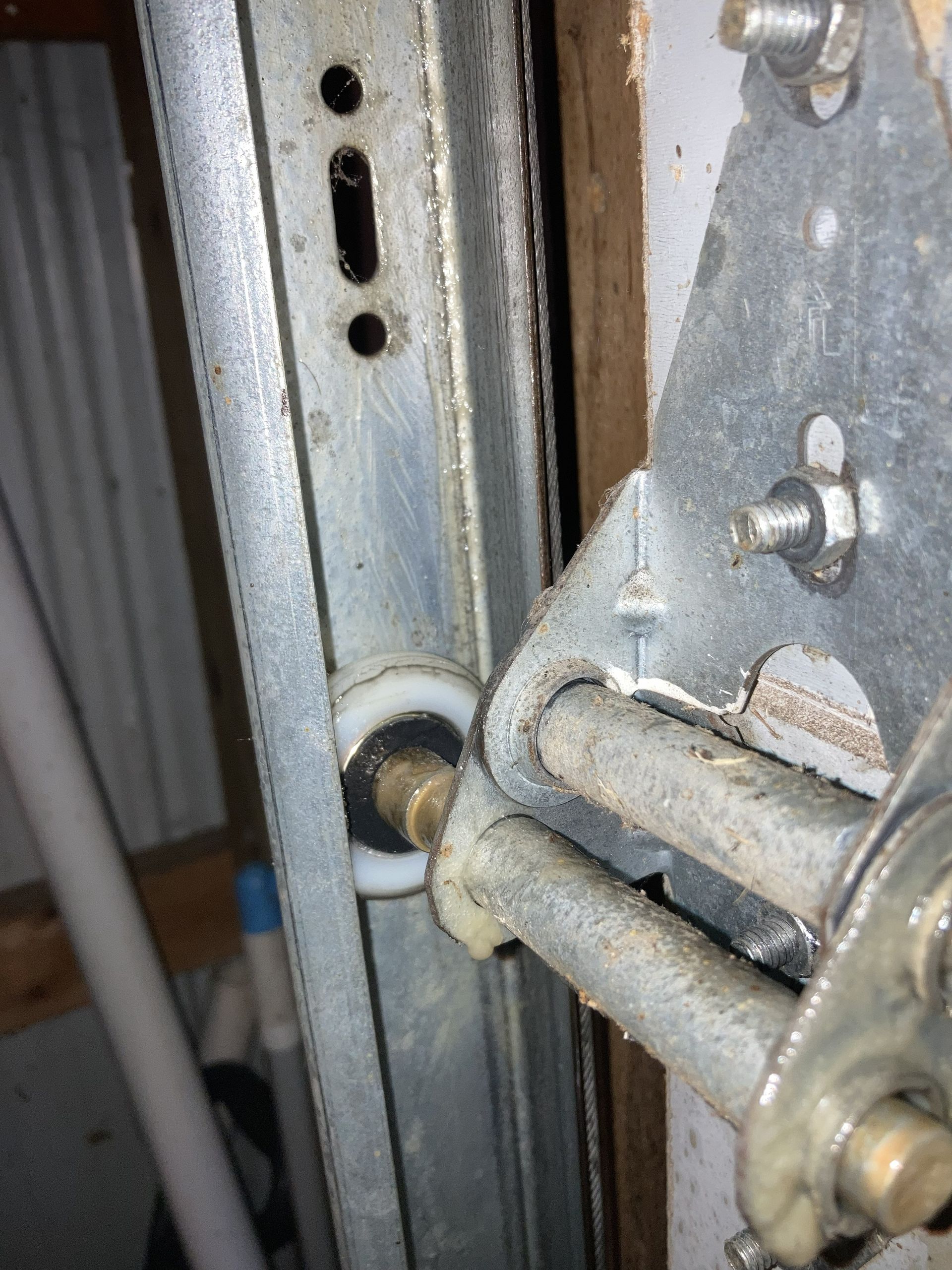 Close-up of a metal door hinge and latch assembly with screws and a worn galvanized frame.