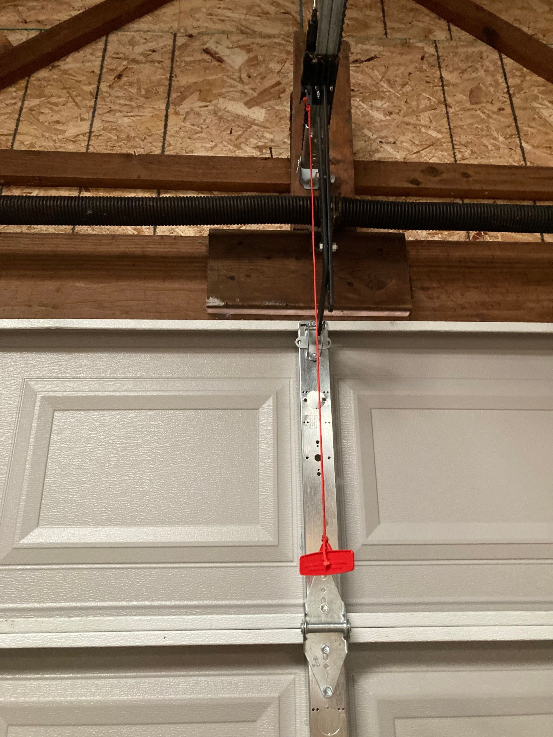 Garage door center with torsion spring and red emergency release cord hanging down