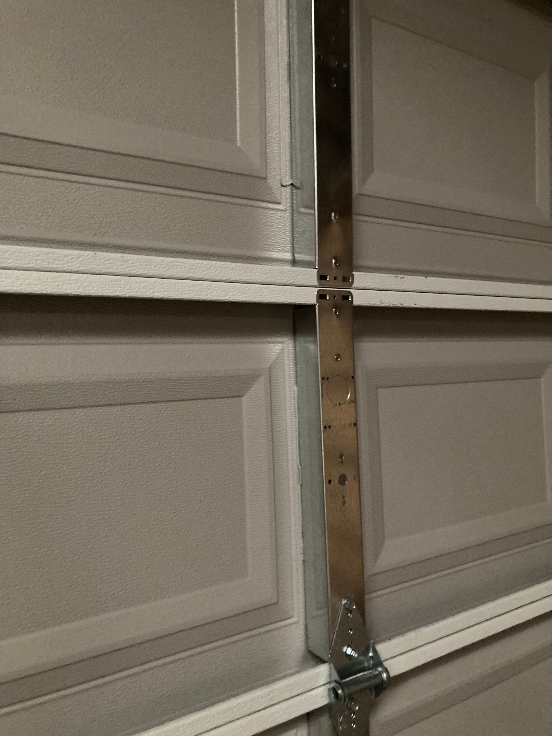 Close-up of a garage door hinge and vertical support bracket with bolts.