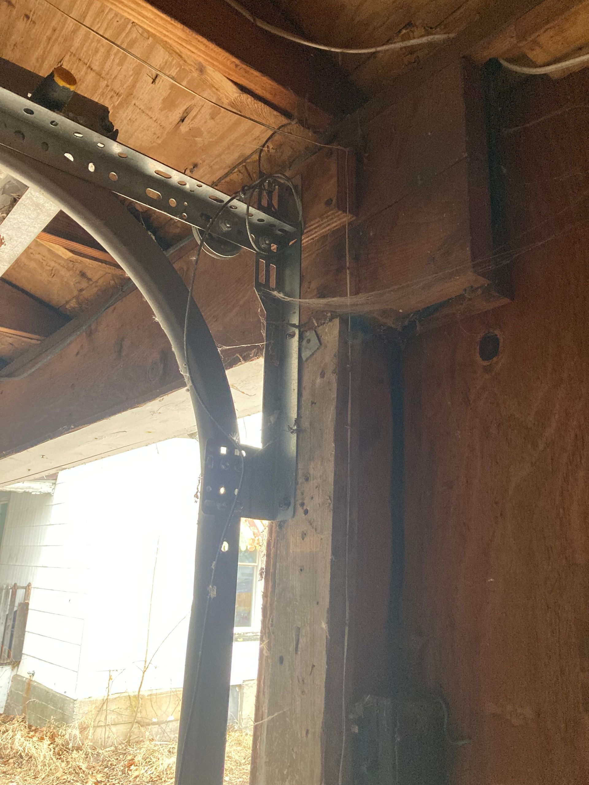 Wooden porch ceiling with metal support posts and a bright window opening on the left.