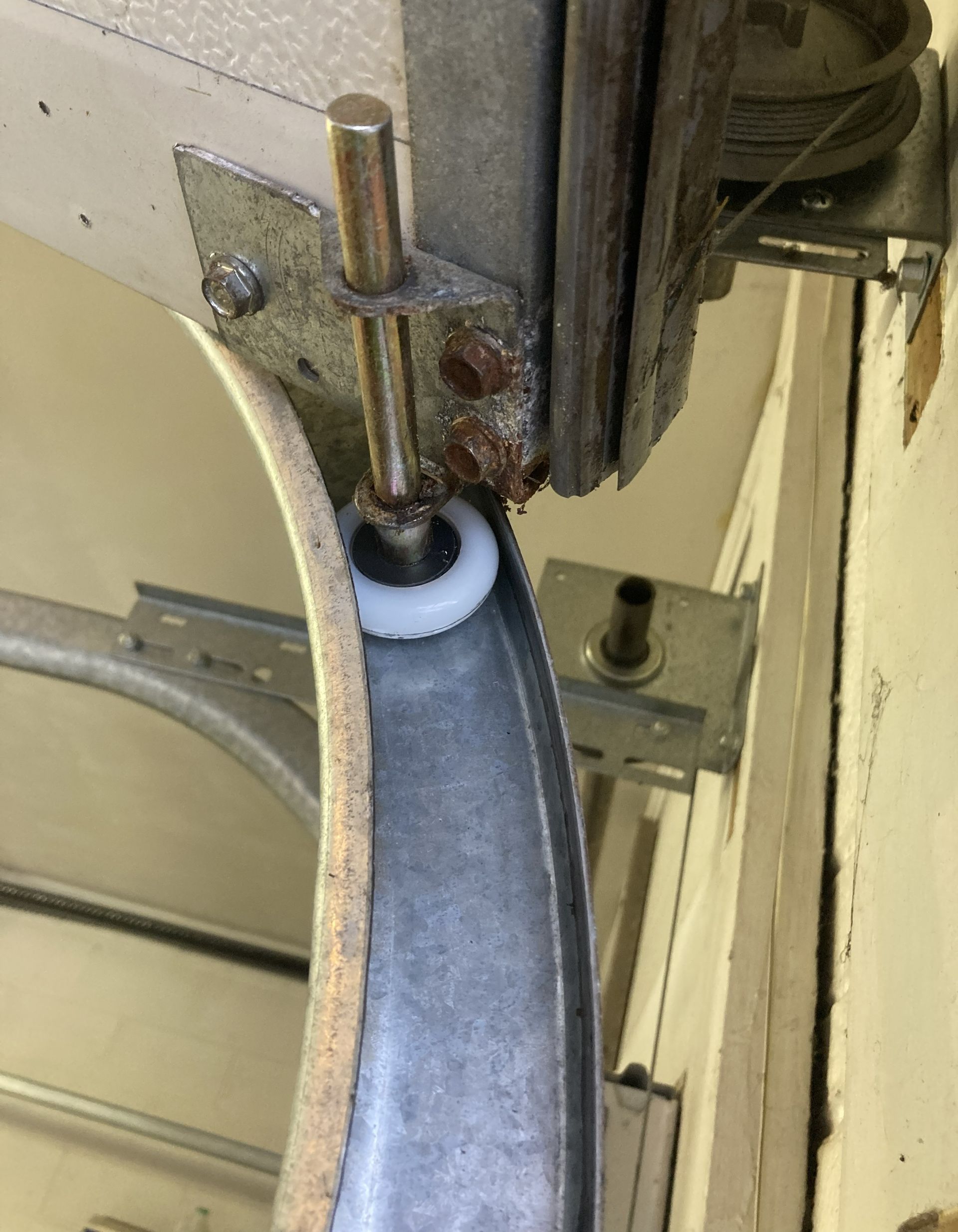 Close-up of a metal machine guide and roller contacting a blue strap or belt.