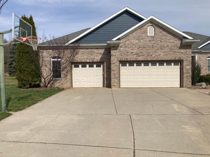Brick suburban house with two garage doors and a wide concrete driveway