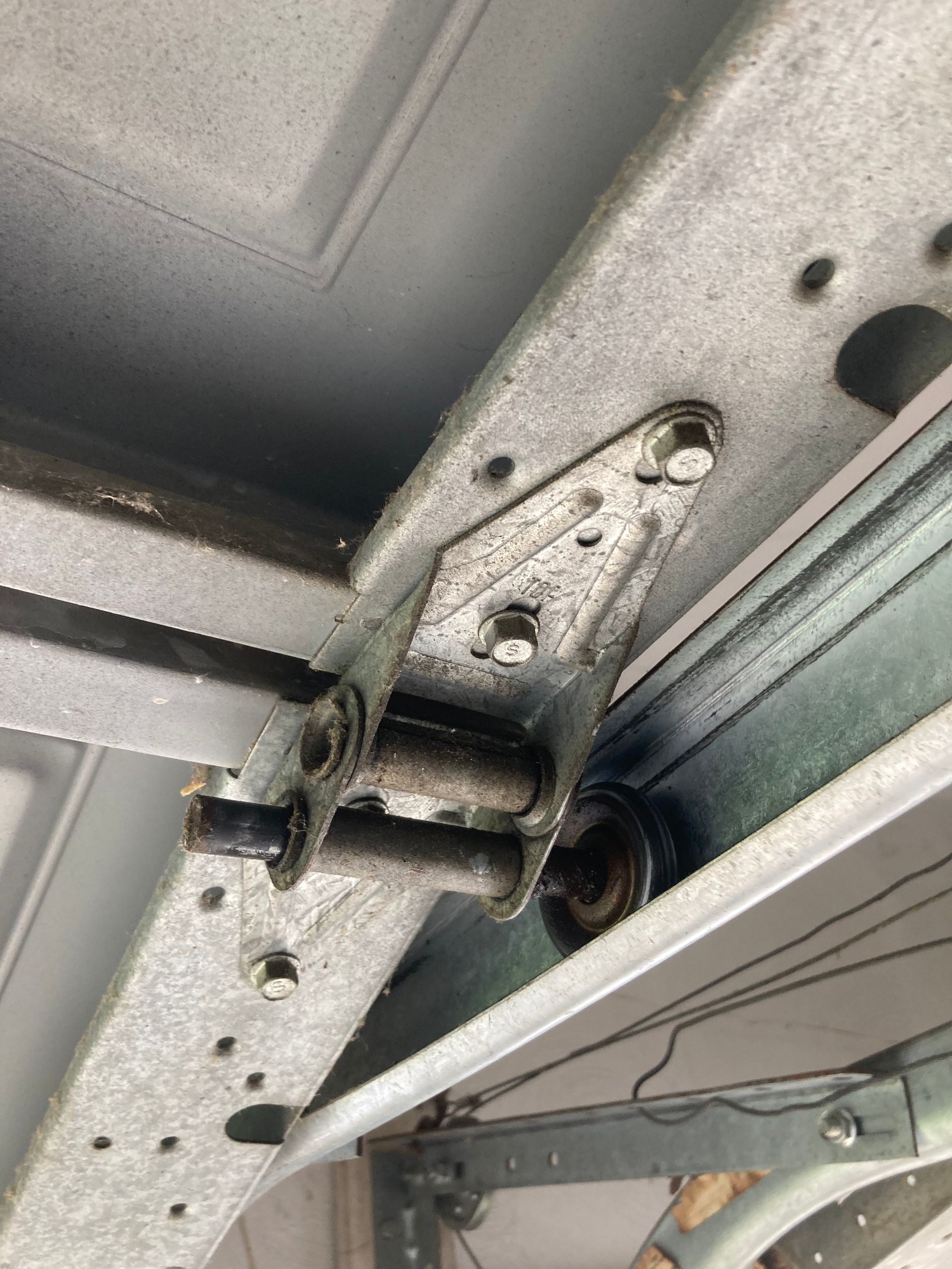 Close-up of a metal garage door hinge and track with visible bolts and brackets.