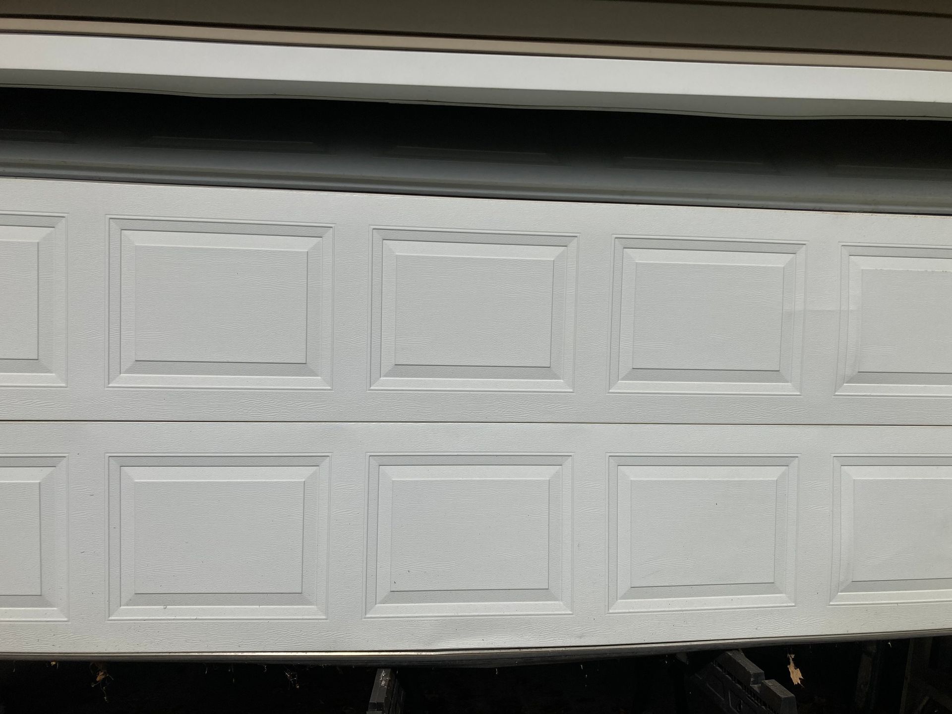 White paneled garage door with a small gap at the top, viewed straight on