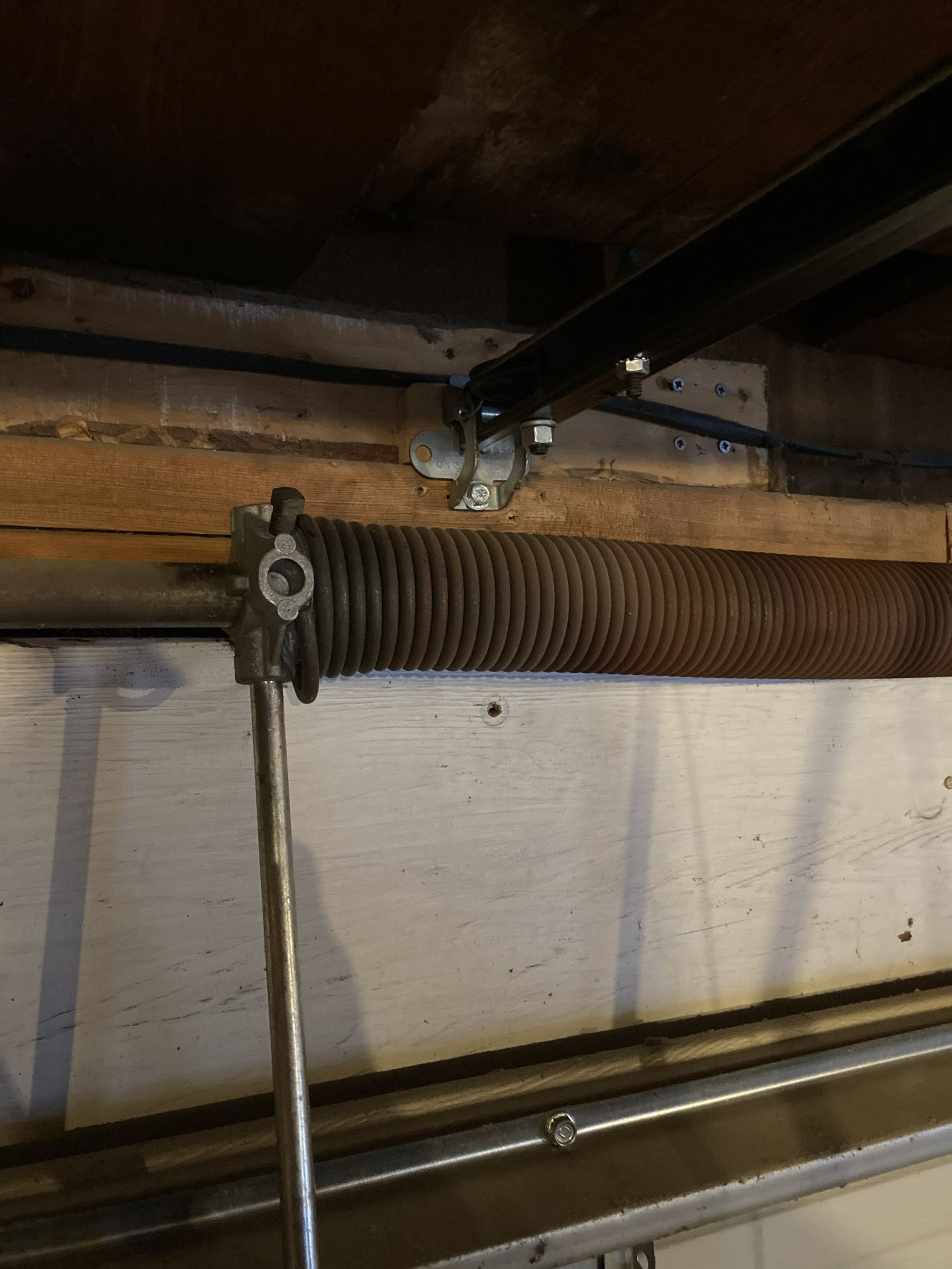 Close-up of a garage door torsion spring and metal track mounted beneath the ceiling.