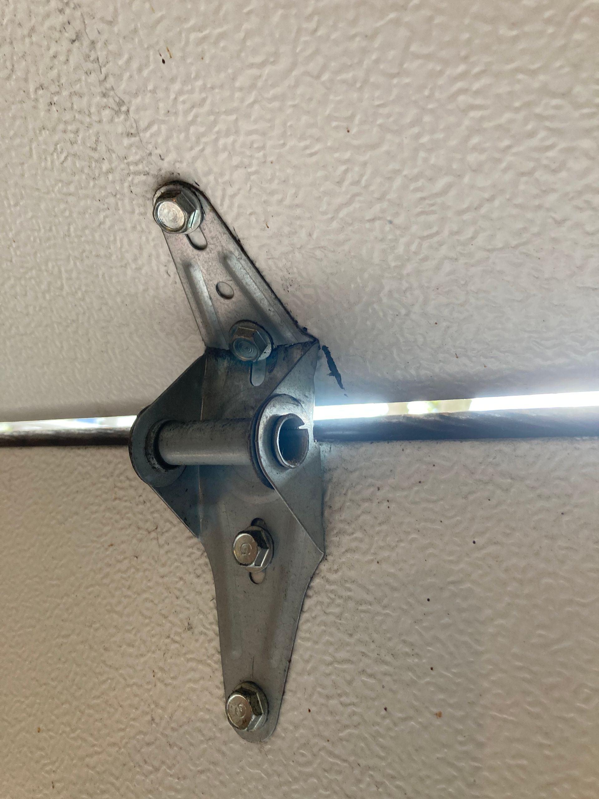 Close-up of a metal curtain rod bracket mounted on a white textured wall