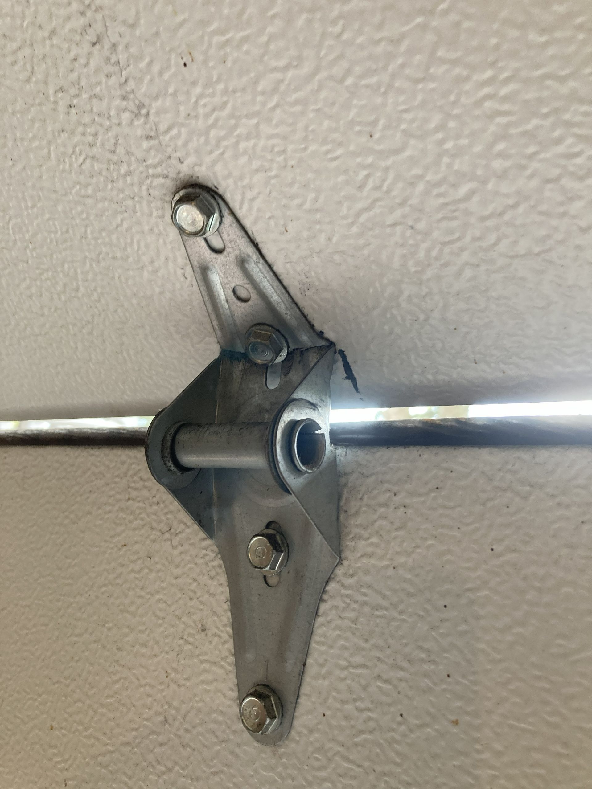 Metal rod bracket mounted to a beige wall ceiling, holding a horizontal chrome rail