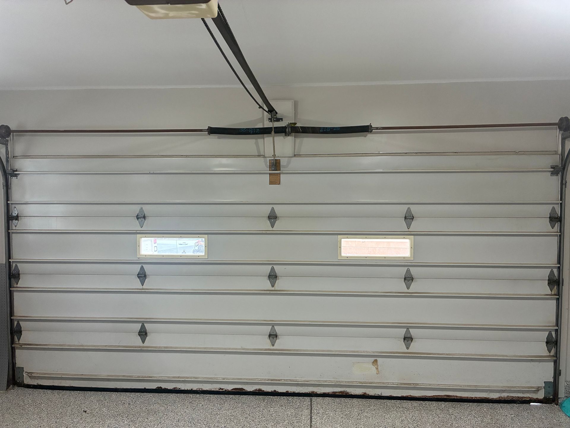 Closed white garage door with small windows in a garage interior