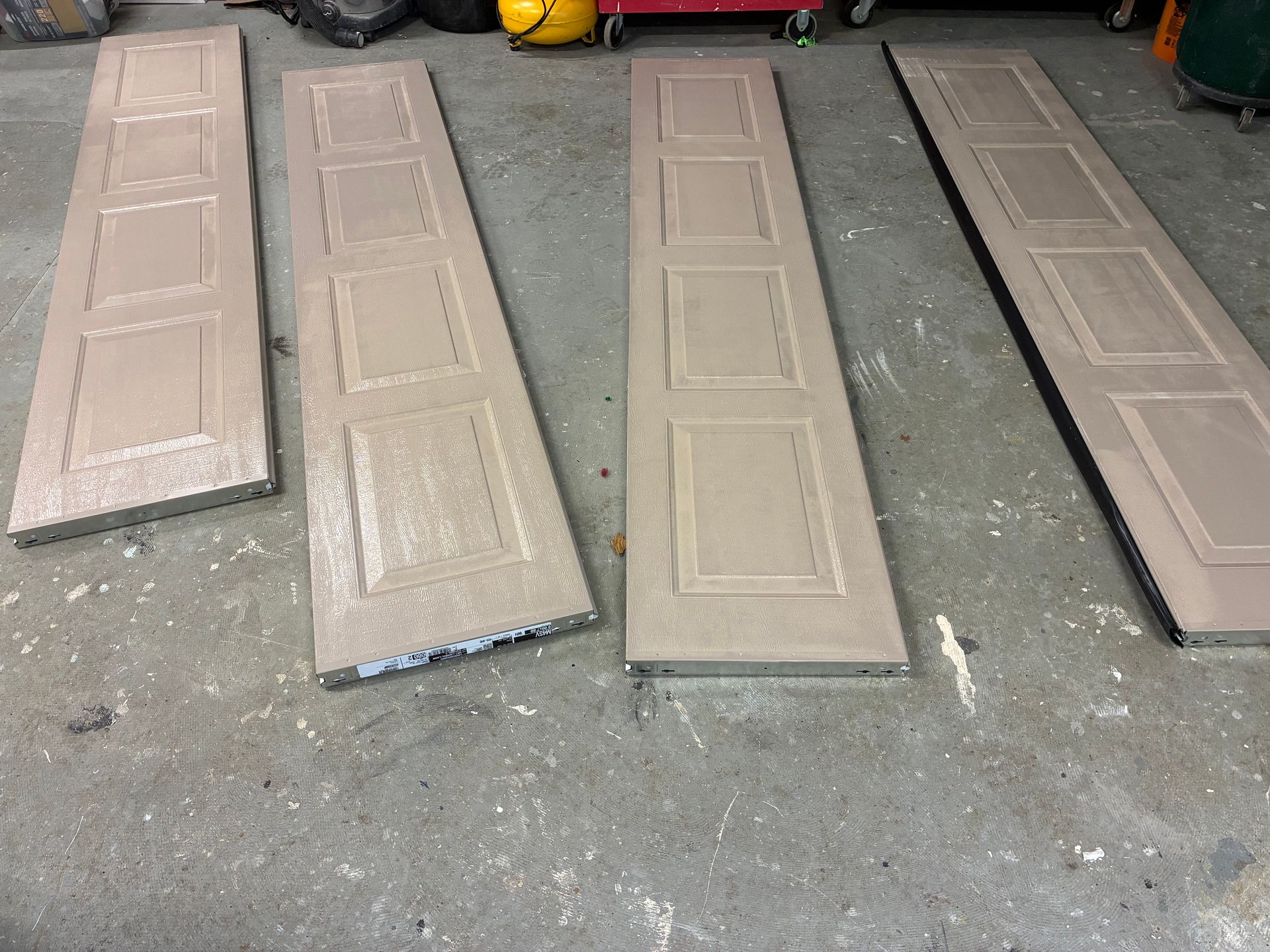Four beige interior doors laid on a garage floor, viewed from above.