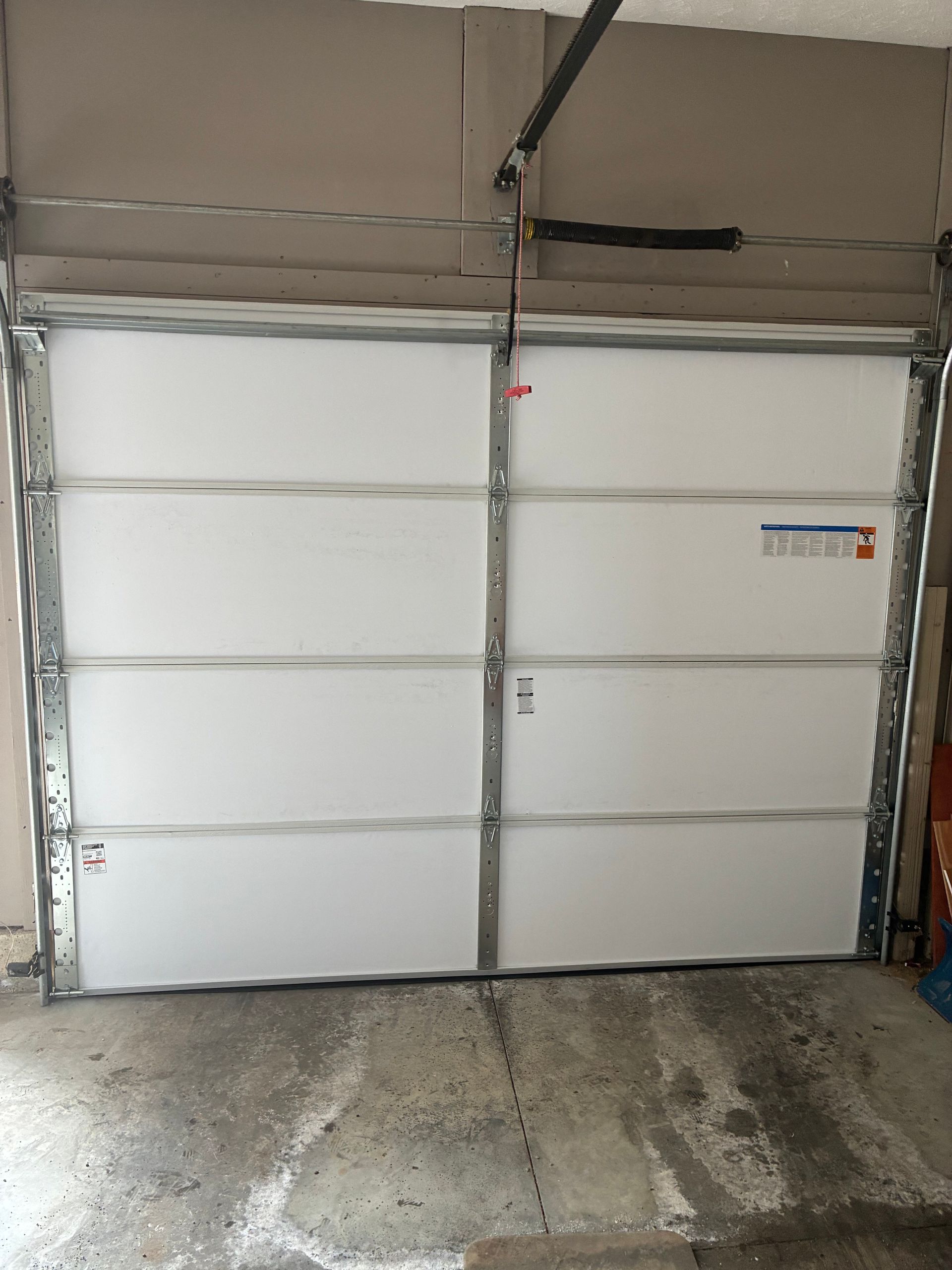 White sectional garage door with metal frame and concrete driveway in front