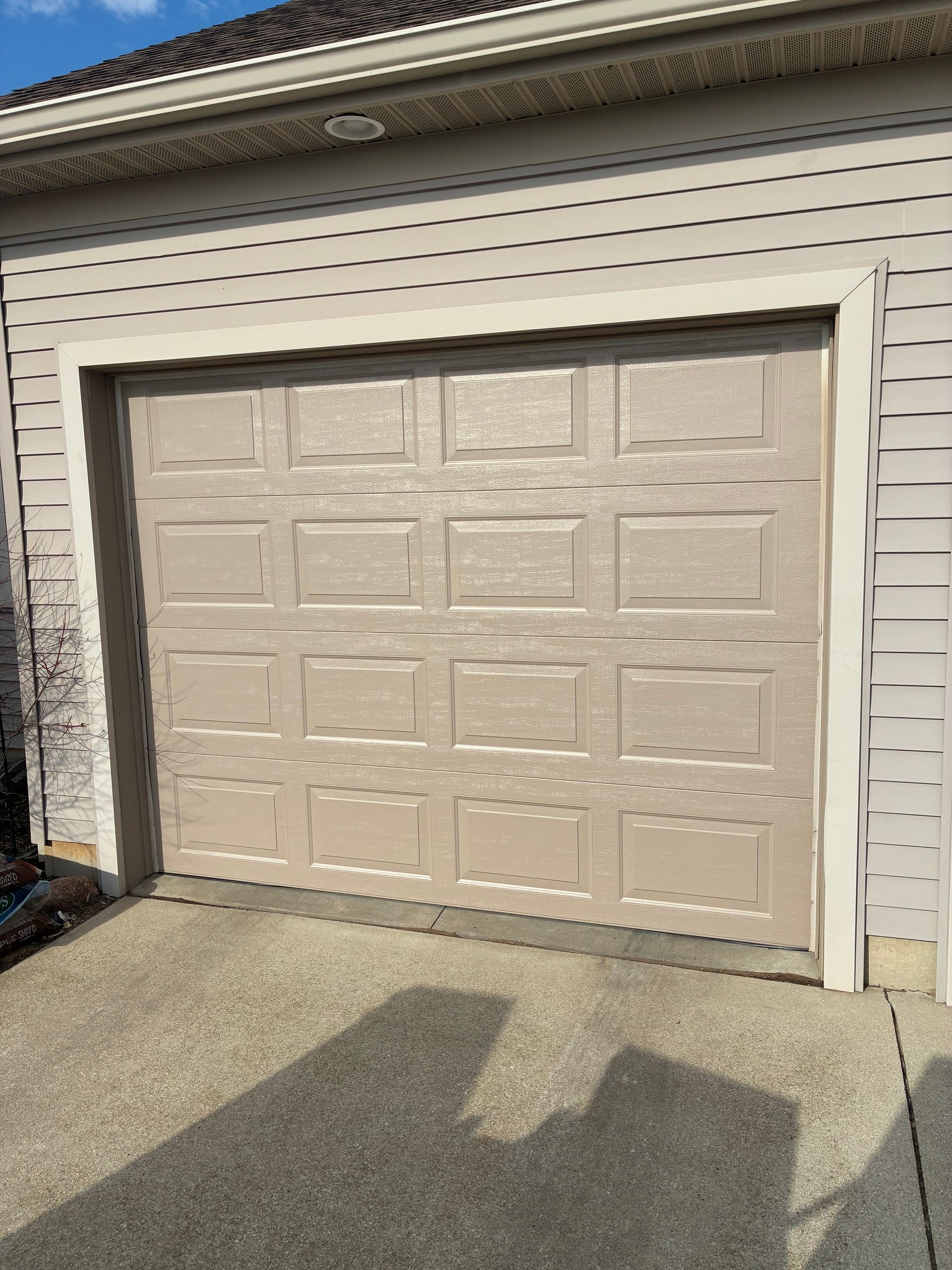 Closed beige garage door with a two-car-wide driveway in front of a house.