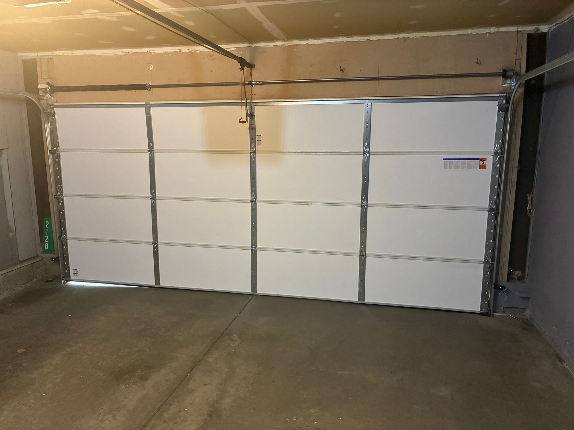Empty garage interior with a closed white sectional garage door and concrete floor.
