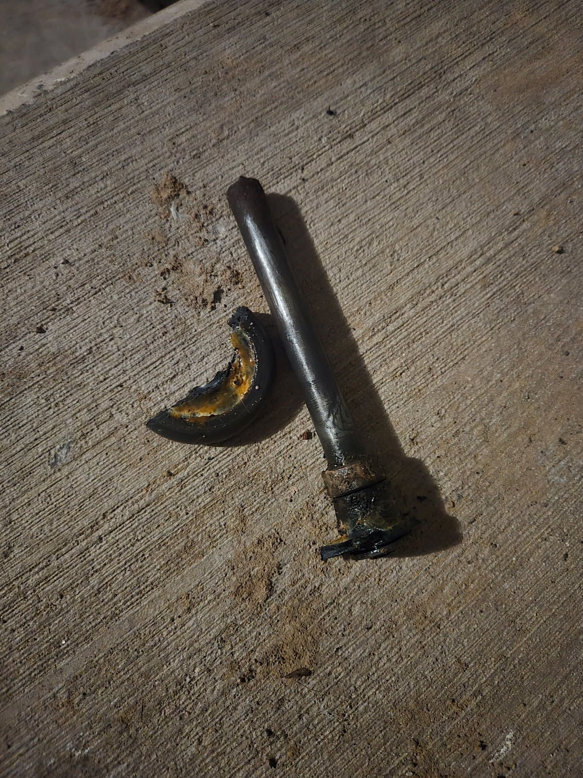Burned cigarette butt and a small charred object on rough concrete surface