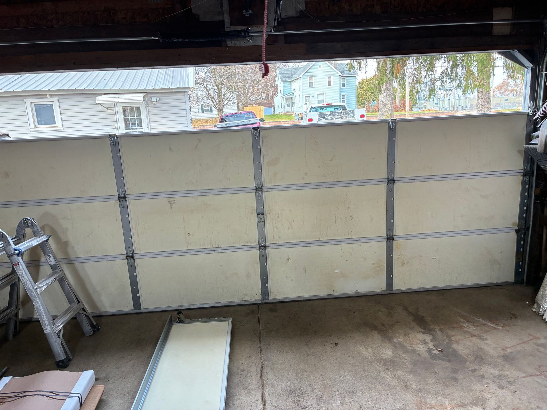 Garage interior with a large insulated panel or door being installed across the opening