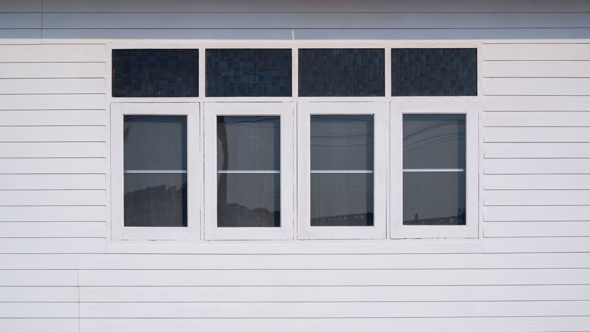 White house exterior with four narrow windows and dark transom panes above them