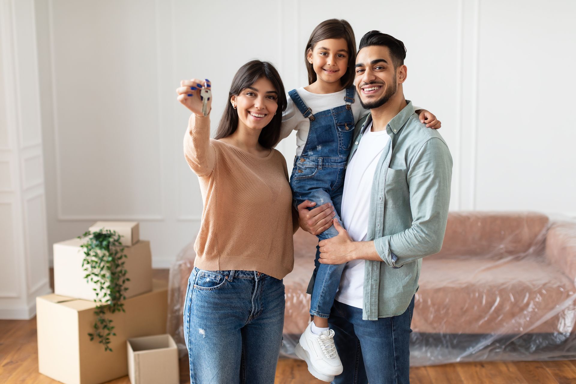 Smiling family taking a selfie in a bright living room with moving boxes and wrapped furniture Smiling family taking a selfie in a bright living room with moving boxes and wrapped furniture