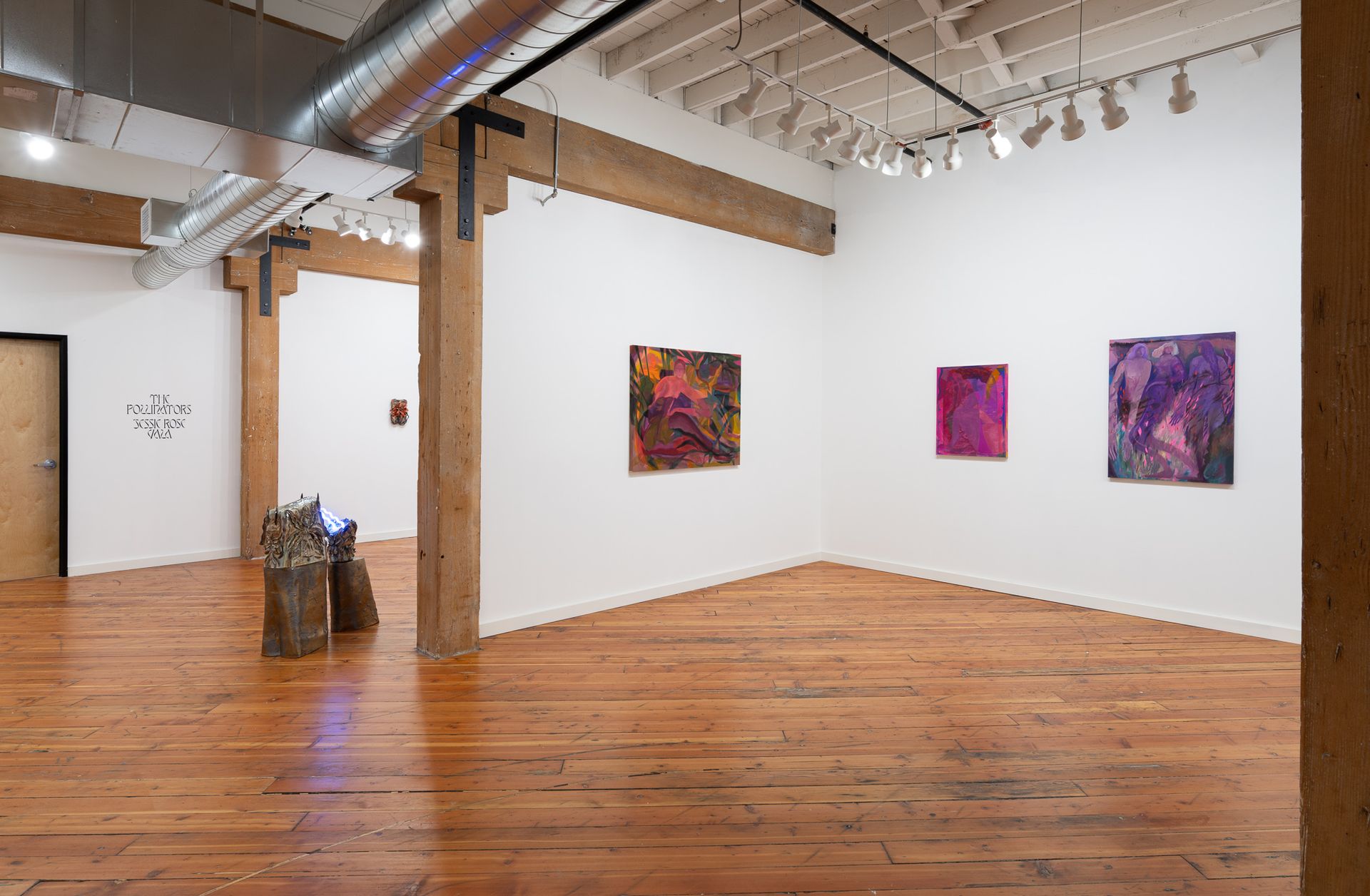 An art gallery interior with wooden floors, white walls, abstract paintings by Emily Elizabeth Wise, and a sculpture.