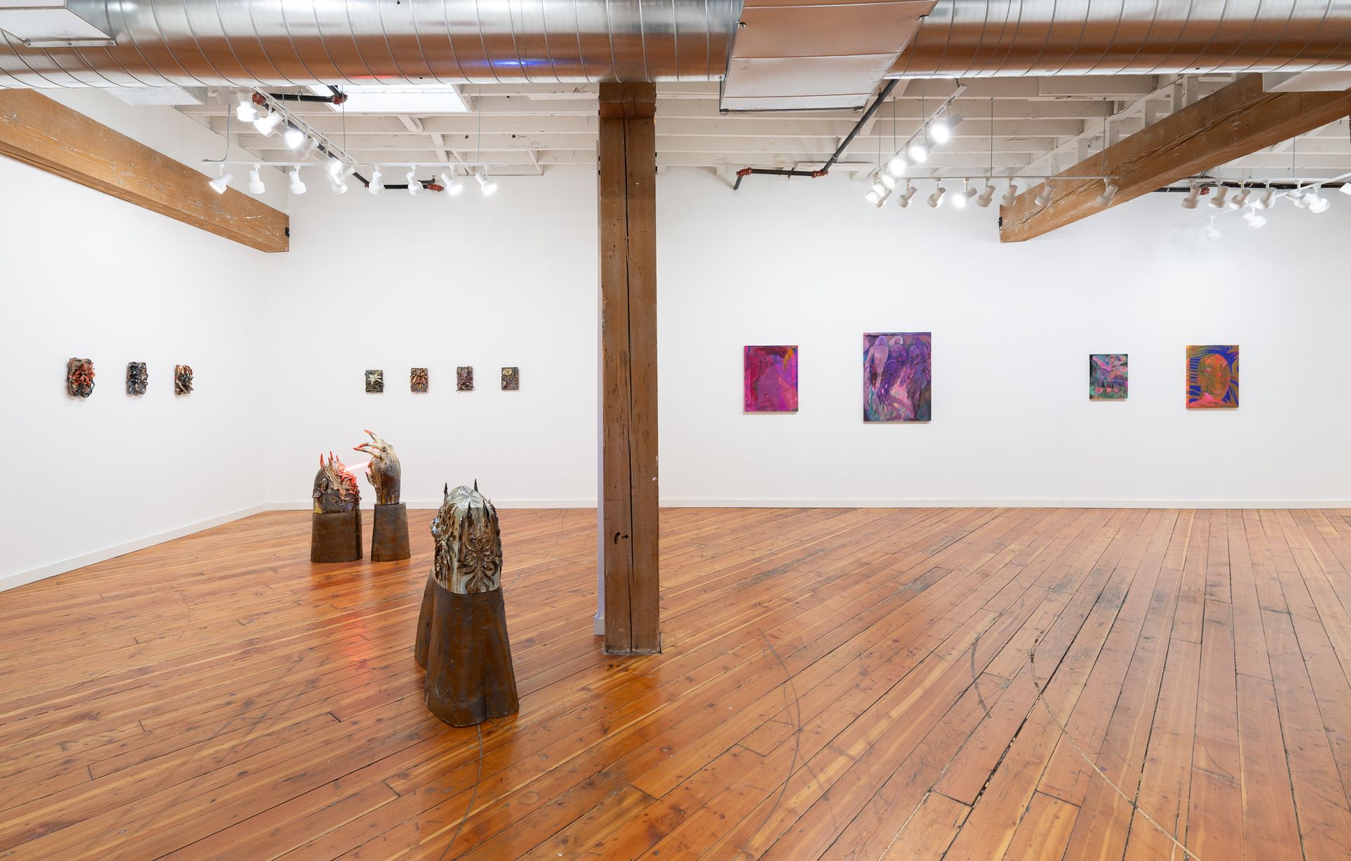 A wide gallery space with wooden floors and columns displays various paintings by Emily Elizabeth Wise.