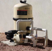 Pool pump and filter system; tan, vertical tank atop a cream-colored pump; white pipes; beige gravel ground.