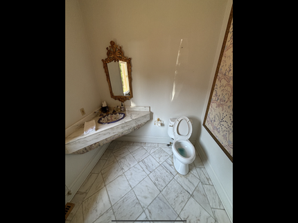 A bathroom with a toilet , sink and mirror.