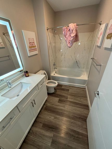 A bathroom with a sink , toilet , tub and mirror.