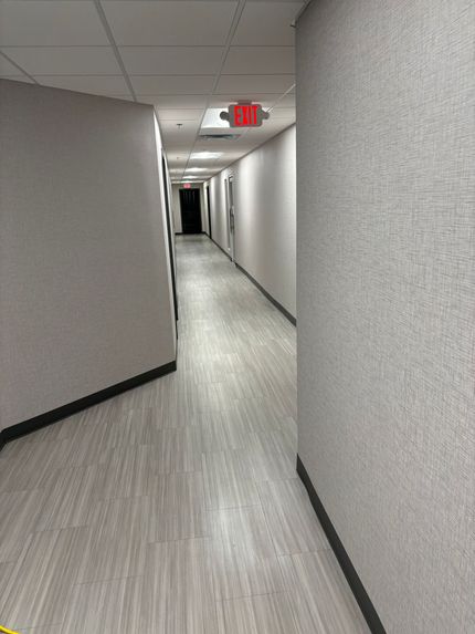 A long hallway with a red exit sign on the ceiling.