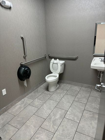 A bathroom with a toilet , sink and mirror.