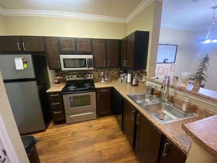A kitchen with a stove , refrigerator , sink and microwave.