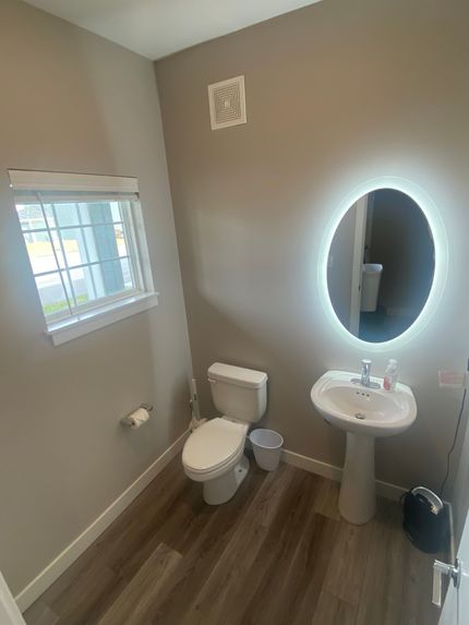 A bathroom with a toilet , sink and mirror.