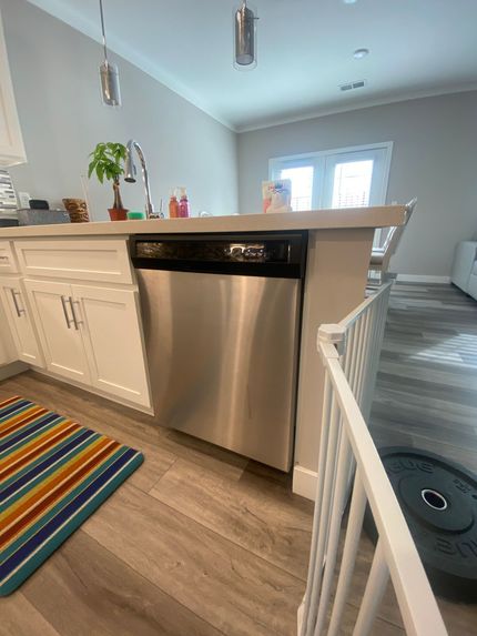 A kitchen with a stainless steel dishwasher and a rug on the floor.