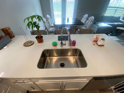 A kitchen with a stainless steel sink and a white counter top